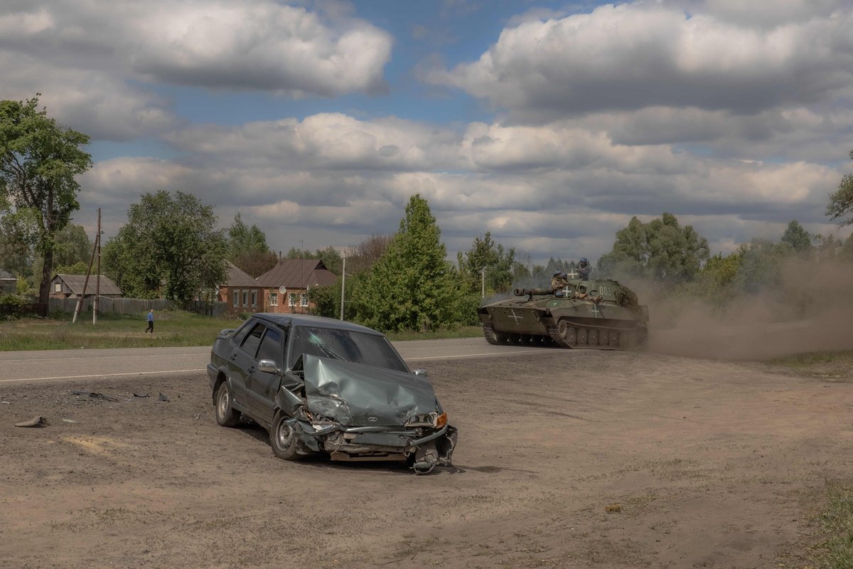 Украинская самоходная гаубица проезжает мимо поврежденного автомобиля на дороге в Волчанском районе Харьковской области, 12 мая 2024 года. Фото: Роман Пилипей / AFP / Scanpix