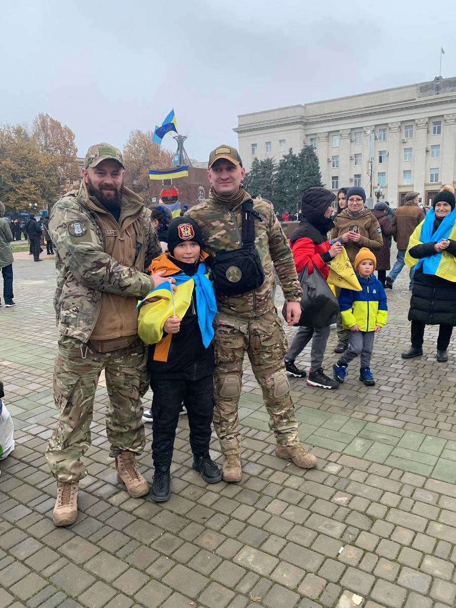 10-летний Максим фотографируется с украинскими военными, они ставят свои автографы на его флаге. Фото: Ольга Мусафирова