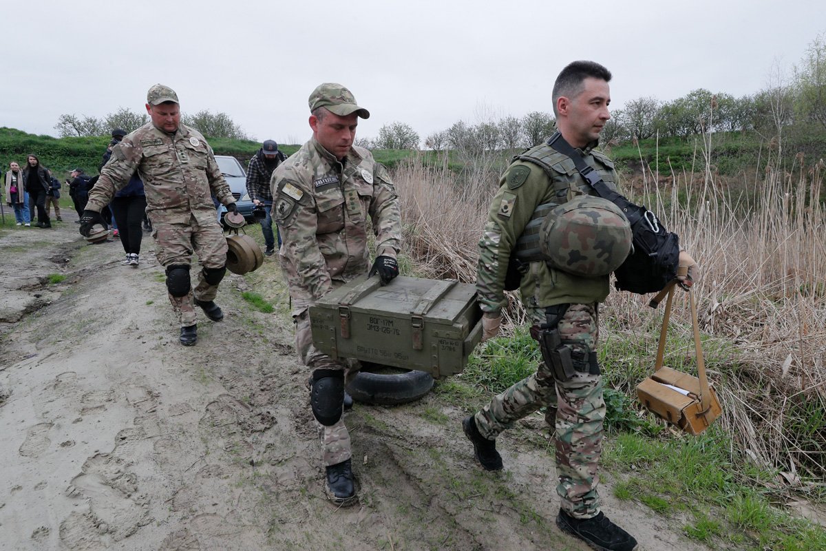 Украинские саперы несут ящики перед уничтожением противотанковых мин и других взрывчатых веществ, обнаруженных возле Бучи на военном полигоне под Киевом, 13 апреля 2023 года. Фото: Сергей Долженко / EPA-EFE