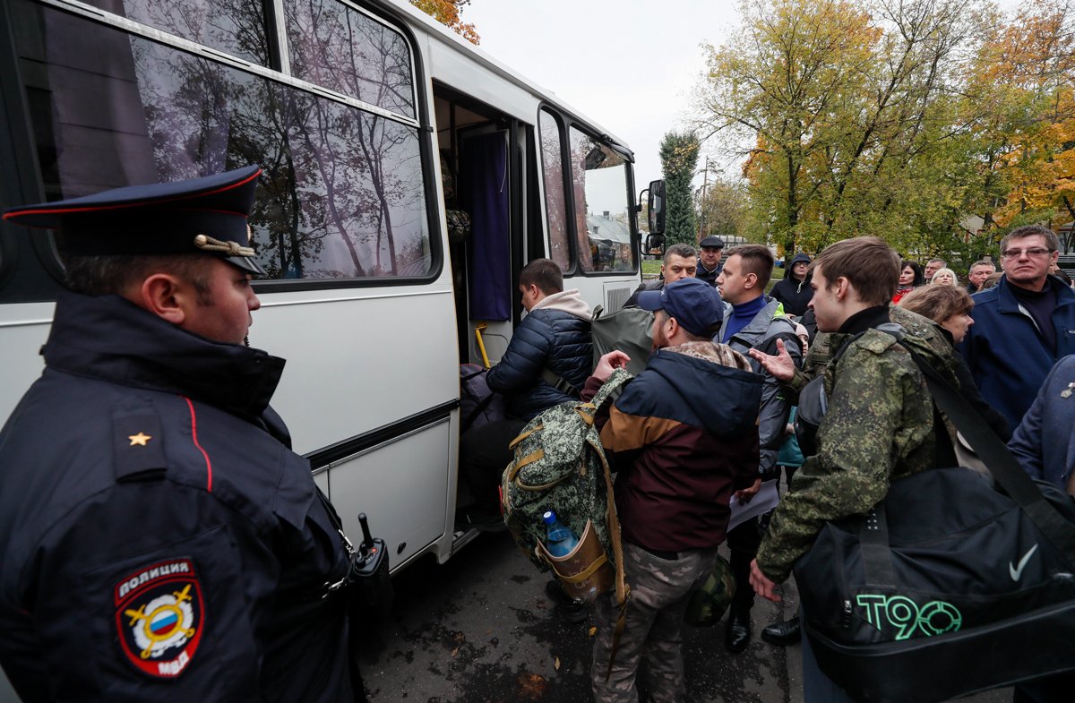 Полицейский на фоне мобилизованных на сборном пункте в Москве, 29 сентября 2022 года. Фото: Юрий Кочетков / EPA-EFE